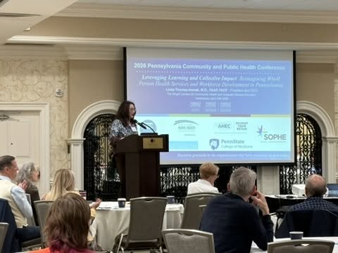 A presenter speaks in front of a crowd at the 2026 Community and Public Health Conference