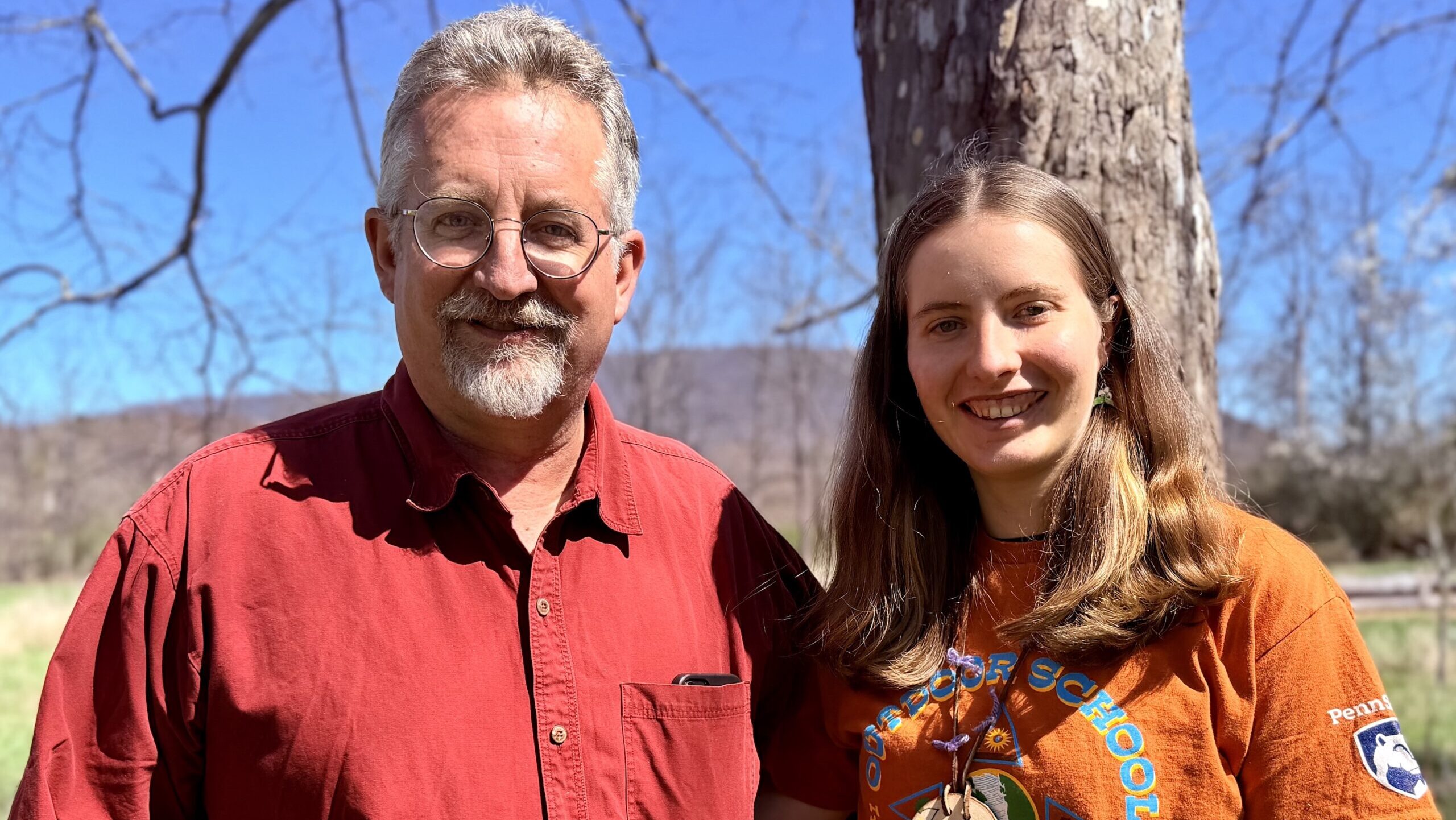 A man and his daughter pose together in a natural setting.