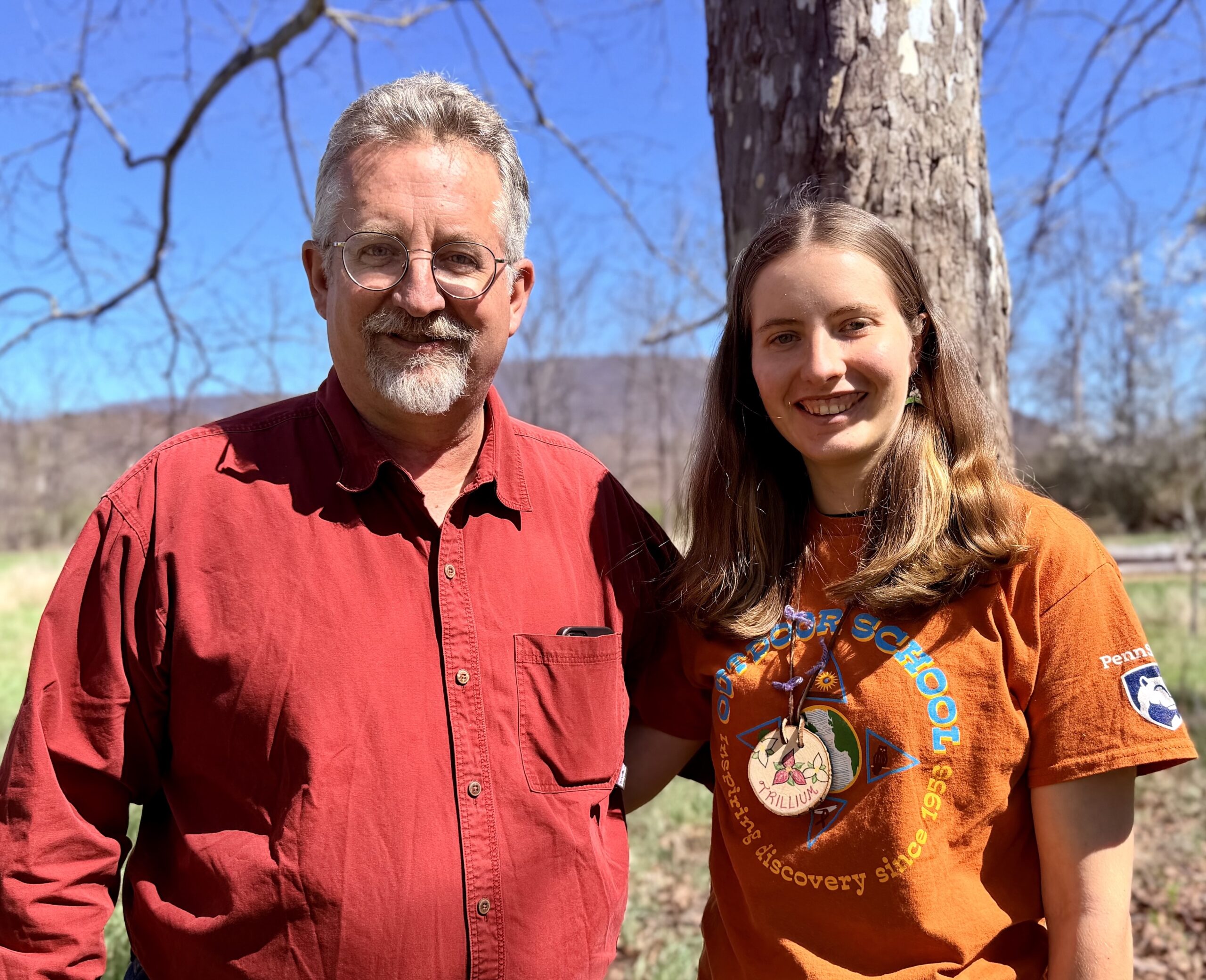 A man and his daughter pose together in a natural setting.