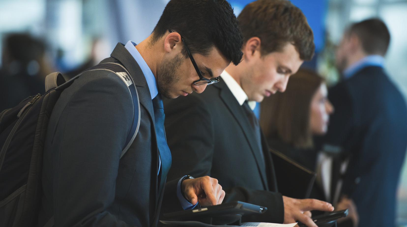Two students wearing professional attire look at their cell phones.