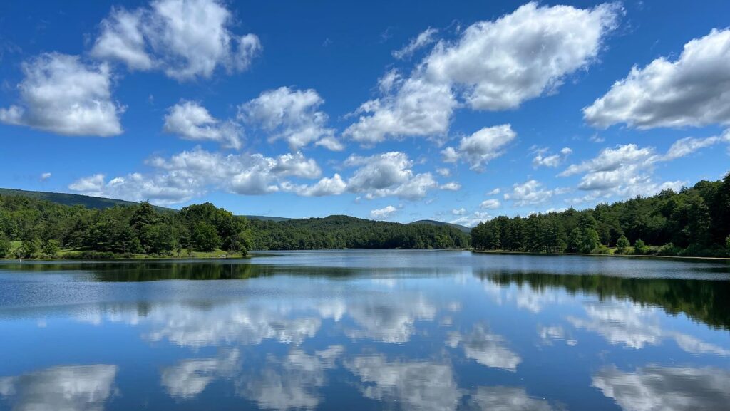 A mirror image of blue skies and puffy white clouds reflected in the still water of Lake Perez.