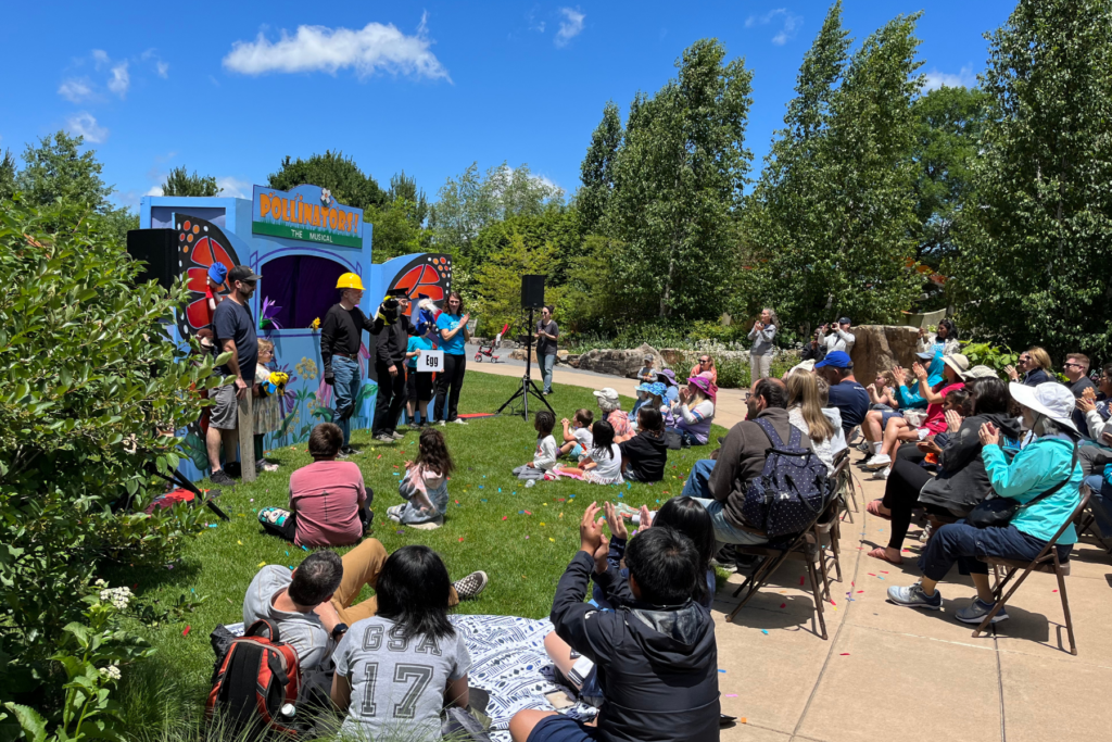 A group of participants gathered around for the Pollinator Puppet Show at the Arboretum