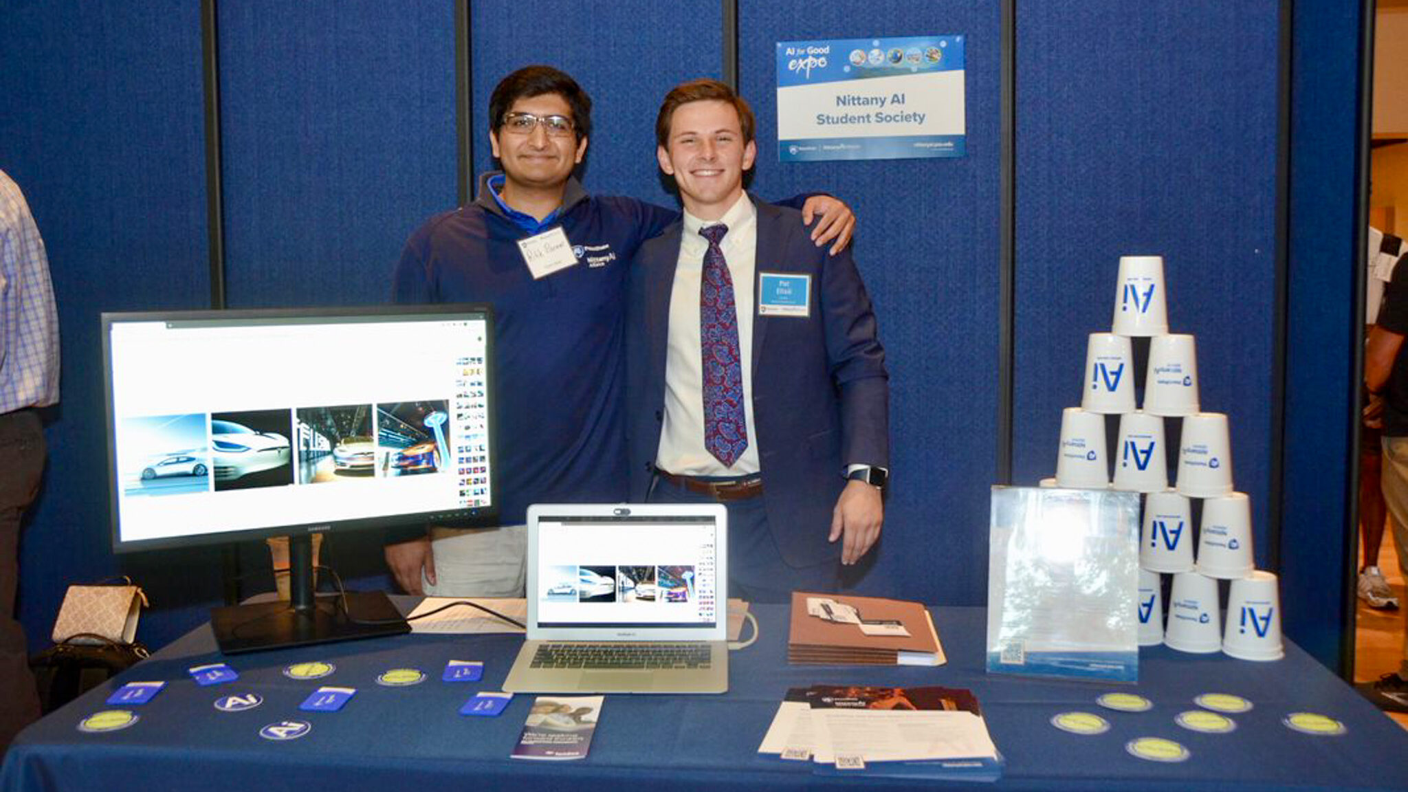 two male students standing at the Nittany AI Student Society table at the 2022 AI for Good Expo