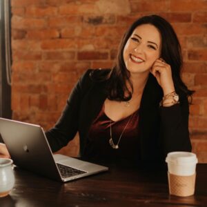 Lindsey Whissel Fenton sitting at a table with her laptop and a cup of coffee