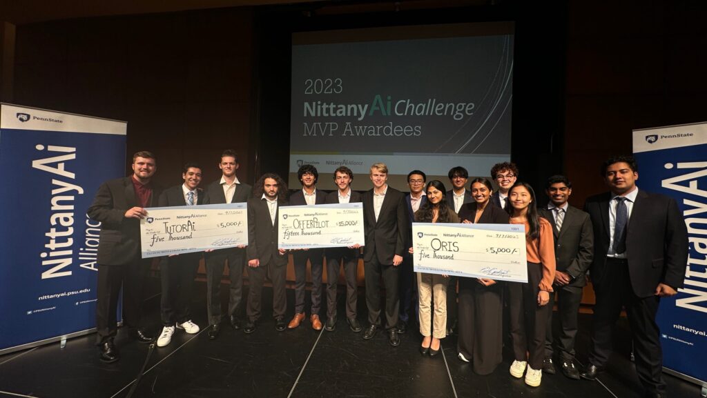 Students from the Nittany AI Challenge on stage with winning checks