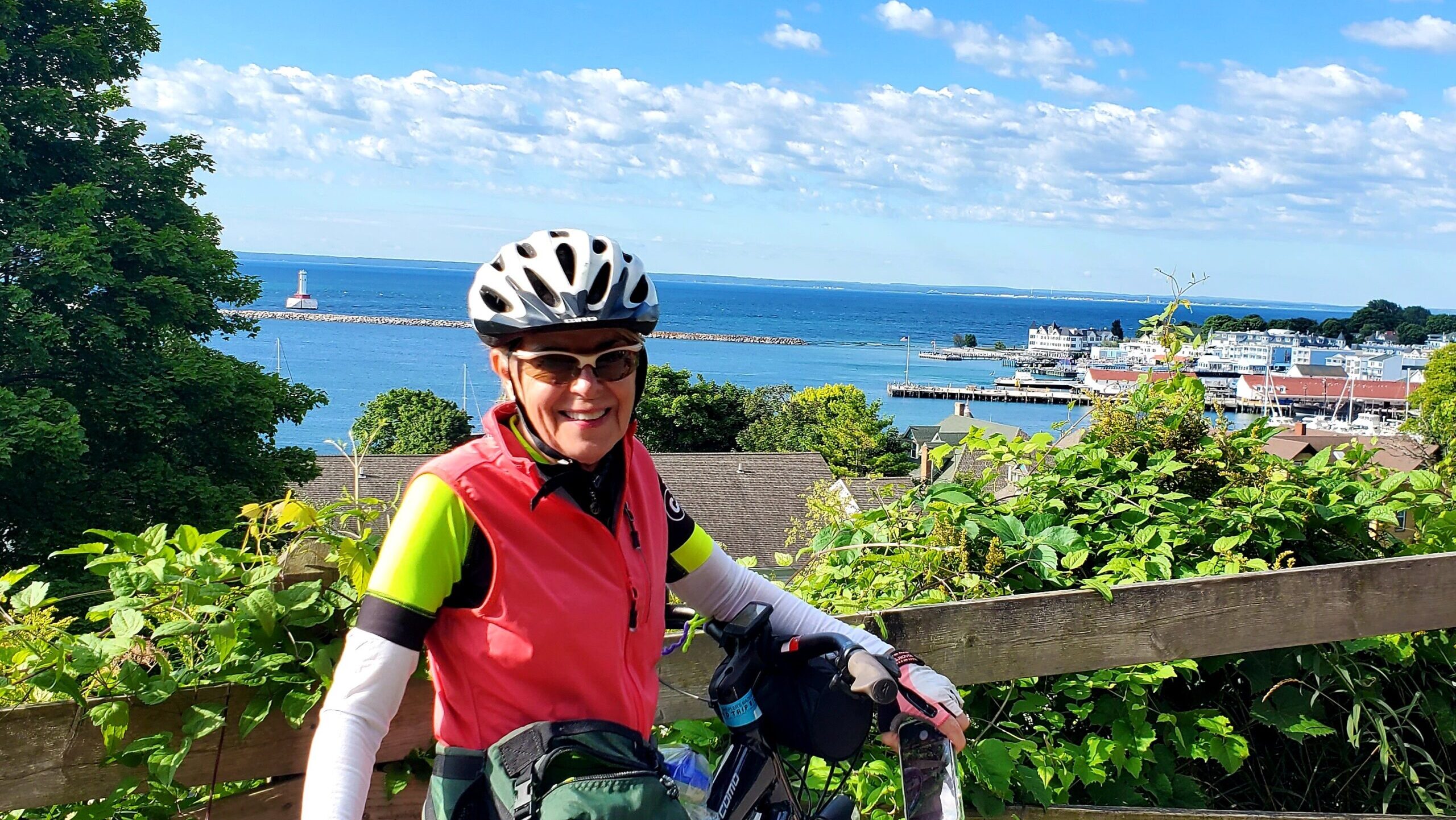 Melinda Stearns wearing a white bike helmet and sunglasses and posing with her bike in front of Lake Michigan.