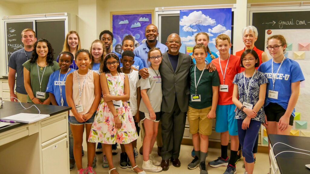 A diverse group of students pose in the front of a classroom