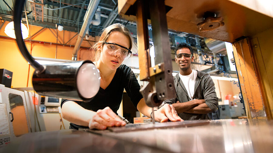 Two students working with cutting tools in a lab